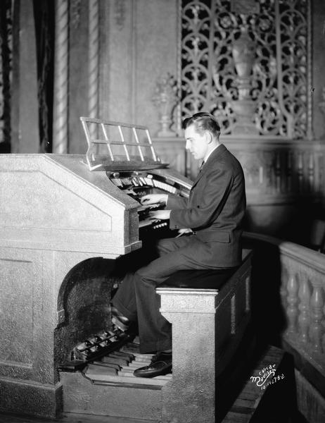 An organist is playing the Eastwood Theatre organ, located at 2090 Atwood Avenue. The organ grill is in the background on the far wall.