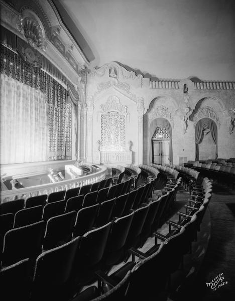 View of the Eastwood Theater proscenium arch, grills, orchestra pit, and front few rows of seating, with decorative detail along the side of the auditorium.