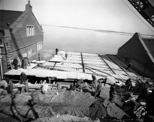 Men working on the concrete forms for the roof of the addition to the University of Wisconsin hydraulics laboratory, 660 N. Park Street looking north over Lake Mendota.