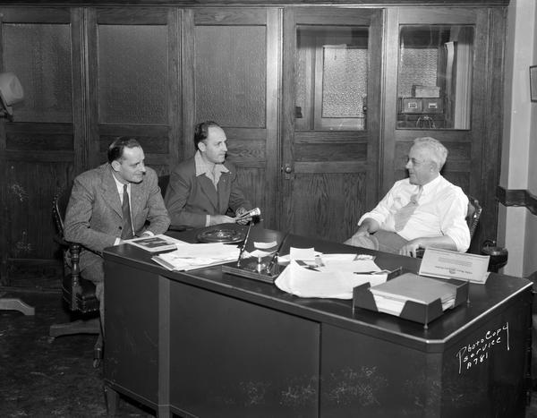 Roy F. Bergengren, Managing Director, at desk with two visitors at the CUNA (Credit Union National Association) office, 1342 East Washington Avenue.
