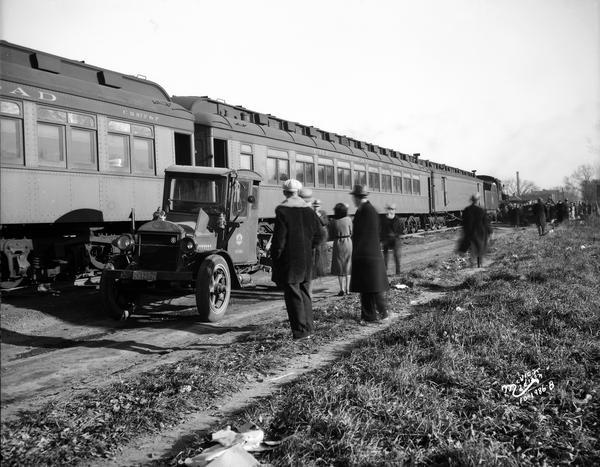 People looking at the train cars and undamaged front end of the Wisconsin Telephone Company truck involved in the Milwaukee Road passenger train-truck accident.