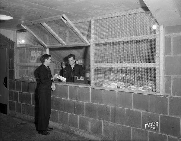 Naval clerk selling Old Gold cigarettes to a trainee at the U.S. Naval Training School (Radio) ship's store in the University of Wisconsin athletic stadium (Camp Randall).
