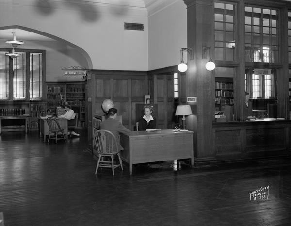Interior of Madison Public Library, 206 North Carroll Street. The view includes the Reference Room, Information Desk, and Return Window with three librarians and one patron.