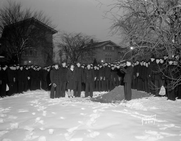 Large group of U.S. Naval Training School (Radio) trainees, at the Van Hise dormitories, standing at the grave site of Sparky, with one man playing taps.  Sparky was the Naval trainees mascot.