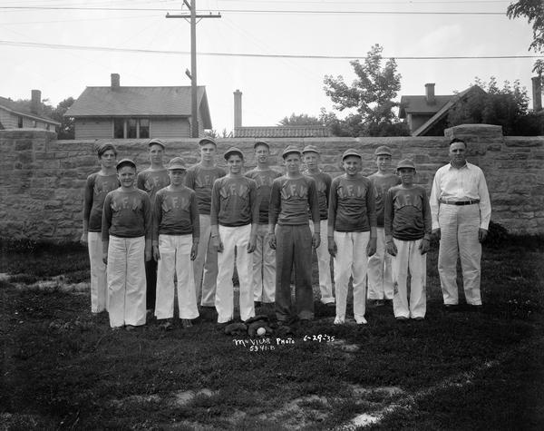 Group portrait of twelve boys on the V.F.W. baseball team in uniform, with the male coach standing on the right.