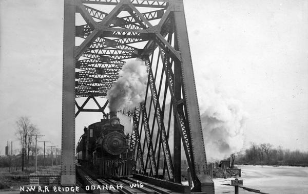 A Northwestern Railroad train pulled by locomotive #967 across a bridge with steel supports.