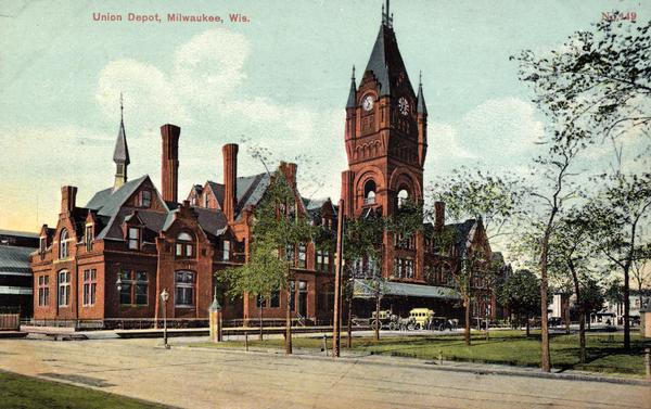 Union Depot with clock tower. The railroad station with clock tower is behind a park. Horse-drawn vehicles are near the entrance. Caption reads: "Union Depot, Milwaukee, Wis."