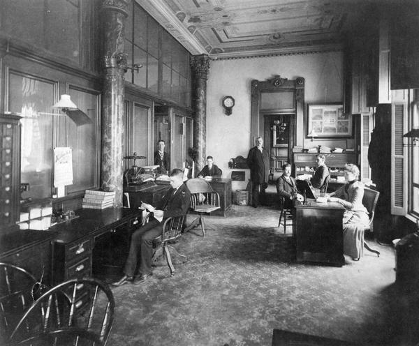General office of the Chicago, Milwaukee, and St. Paul Railway Company in the Mitchell Building in Milwaukee. Left to right: the individual seated in left foreground is unknown; standing, William Kenally; seated, unknown; standing in doorway, D.W. Keyes; seated, O.F. Bird; seated, David Harlowe; and seated, Mary Miller.
