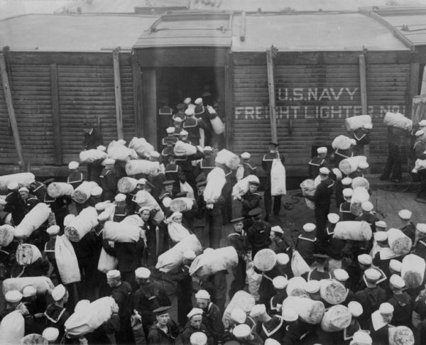 Elevated view of Navy recruits at Newport, boarding a train destined for the Brooklyn Navy Yard. The printed caption indicates that they had had only eight days of training.