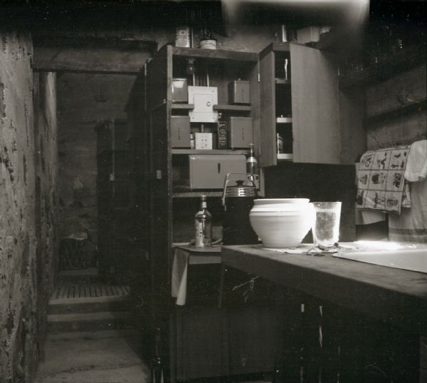 A kitchen work area and cabinets at Taliesin West, winter residence of Frank Lloyd Wright. The cabinets are open revealing storage tins and an electrical box.