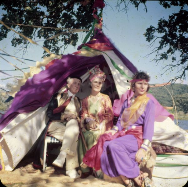 Frank Lloyd Wright and family dressed in costume sitting in front of a tent at a carnival on the grounds of Taliesin. Taliesin was the summer residence of Frank Lloyd Wright and the Taliesin Fellowship.Taliesin is located in the vicinity of Spring Green, Wisconsin.