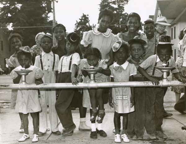 A group of African American children drinking from water fountains, or bubblers as they are frequently known in Milwaukee, at the Wisconsin State Fair.