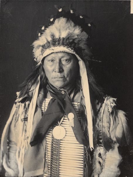 Studio portrait of Chief Mato-He-Hlogeco or Matho-Hexaloketca or Hu-Hu-Lo (Hollow Horn Bear or Bones) or Hoo-Hoo (The Bone), Son of Maza-Pankisko (Iron Shell), in native dress with peace medal, headdress and breastplate. Part of Siouan (Sioux) and Brule Tribes.