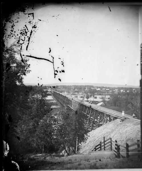 View, from the south bank of the Wisconsin River, looking towards Merrimac, Sauk County.  People are standing on the 1899-foot railroad bridge, which runs from foreground to background in the photograph.