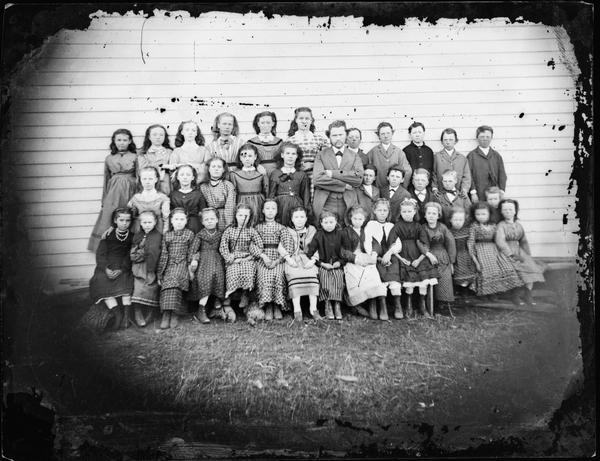 School class with twenty-six girls, ten boys and male teacher in center.