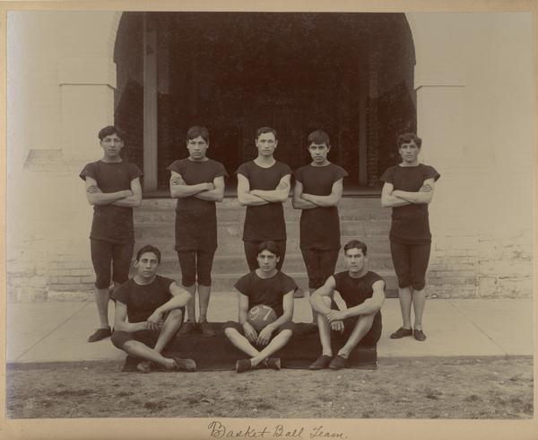 The 1897 Indian Industrial School basketball team, posed for a group portrait in front of the entrance to the gymnasium.