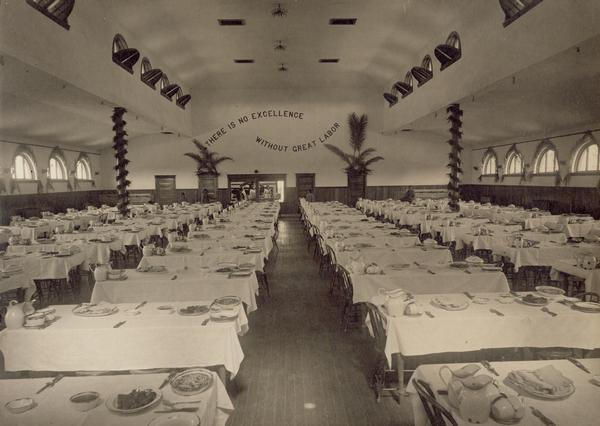 A view of the interior of a Pima Agency dining hall.  The wall reads, "There is no excellence without great labor."