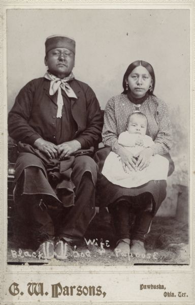 Full-length studio portrait of Black Dog, wife, and papoose sitting.