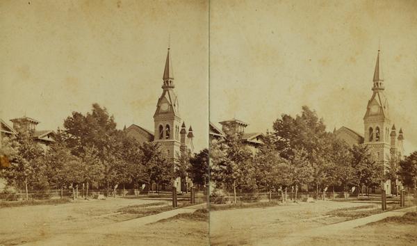 Stereograph of a Methodist Church with a lawn, trees and a fence.