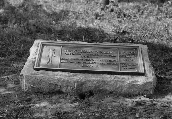 Historic site marker to commemorate Man Mound and to mark Man Mound Park. The inscription reads "Man Mound Park. Mound located and platted by W.H. Canfield in 1859. Length 214 ft., width at shoulders 48 feet."  The tablet was unveiled on August 7, 1908.