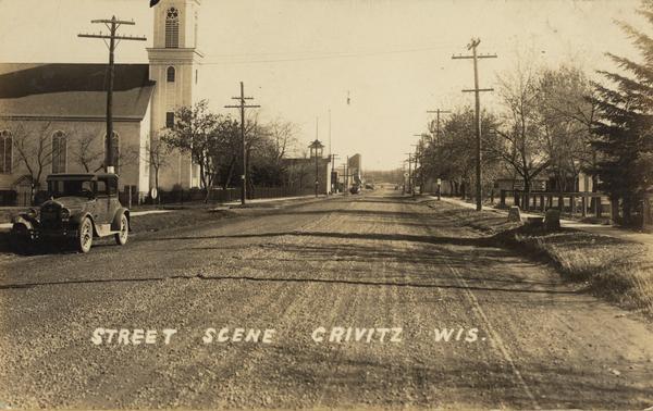 View down center of one of the major streets. Caption reads: "Street Scene, Crivitz Wis." There is a church building on the left side.