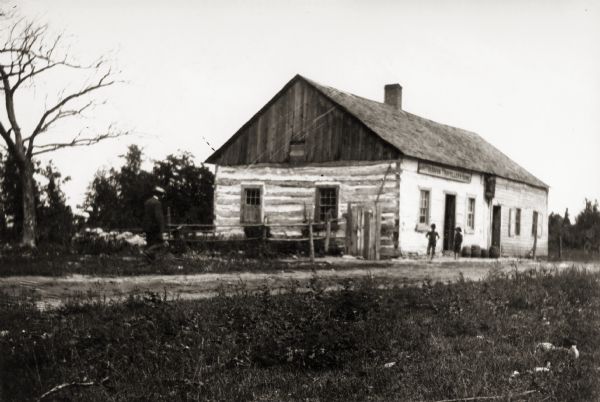 Log house located at the top of Collard's Hill. Two children are standing near the house.