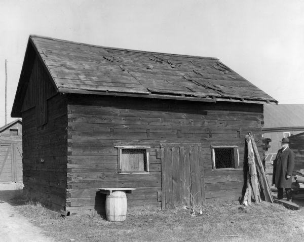 View of a Vincent Roy storage building, with a man standing to the right of the structure.