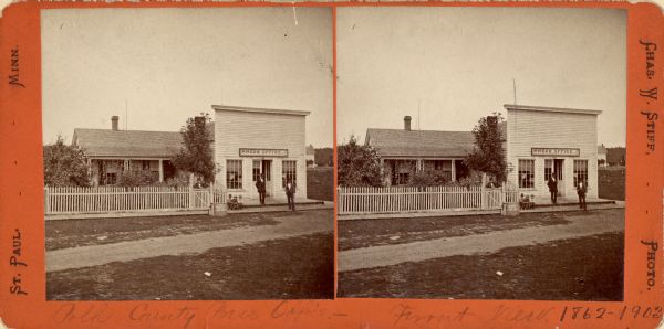 Exterior stereograph of the Polk County Press Office, with three men standing near the entrance, and three children sitting on the left on the board sidewalk.