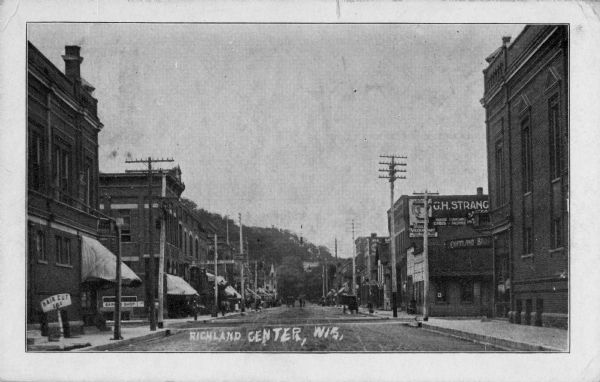 View down a business-lined street featuring a barber shop in the left foreground. Caption reads: "Richland Center, Wis."