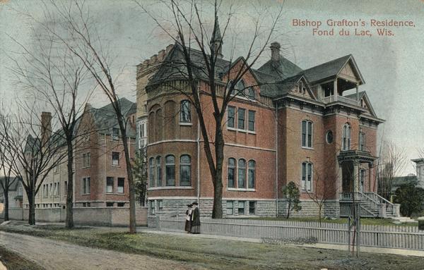 View across road towards two women standing on the sidewalk in front of Bishop Grafton's residence. Caption reads: "Bishop Grafton's Residence, Fond du Lac, Wis."