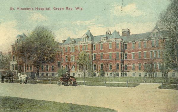 View across street toward the hospital, with horses and carriages along the curb in the foreground. Caption reads: "St. Vincent's Hospital, Green Bay, Wis."