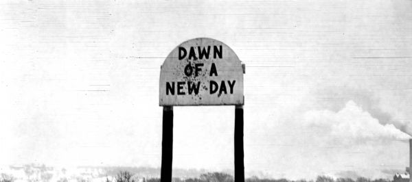 Sign reads: "Dawn of a New Day". The Grignon house was built (at the later address of 1313 Augustine Street) in 1836 by Charles Grignon. Charles Grignon was the son of Augustin Grignon, one of Wisconsin's first permanent white settlers. Charles paid for the construction of the house in part with the money he received for negotiating a treaty with the Menominee Indians. 
Both workmen and materials for the house were brought in from Buffalo, N.Y., then up the Fox River by canoe to the location. The frame structure was built in the Greek Revival style, with fine wood interior, newell post and cherry stair rail, five fireplaces and originally eleven bedrooms. 
The house was originally called "The Mansion in the Woods" and is located in the setting of 100-year-old elms. It was occupied until 1933 and the house served variously as an inn, church, trading post and, later, a museum. The Grignon house was restored in 1940-1941. It then was represented on the Historic American Buildings Survey and the National  Register of Historic Places.