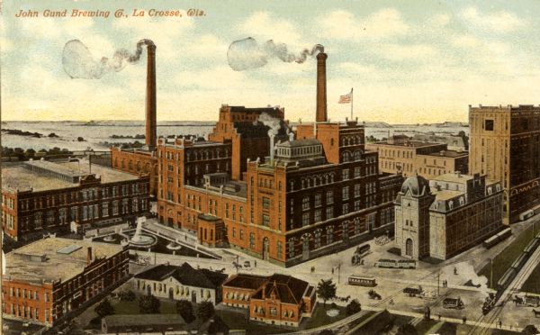 Elevated view of the John Gund Brewing Company buildings, with the Mississippi River in the background. Caption reads: "John Gund Brewing Co., La Crosse, Wis."