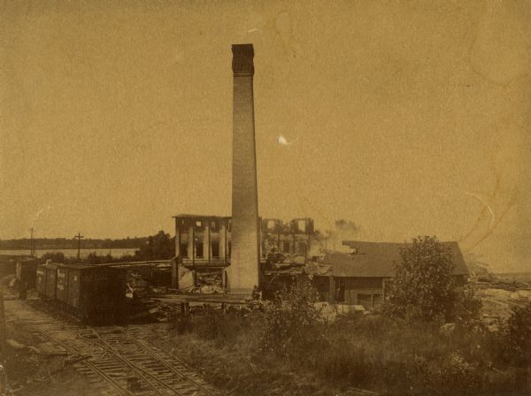 The George A. Whiting Paper Mill after a fire on August 24, 1888. Sixteen men were killed by the explosion of a bleacher; the bleacher exploded as the night fire-man had no time to turn off the steam as he escaped the fire. The bleacher hit the office (the building to the right of the chimney) and landed on the rails where the sixteen men that were killed were standing.