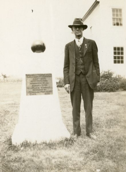 A shell of the Civil War period, recovered from the Mississippi River near Vicksburg, Mississippi, and presented to the First Capitol State Park by the GAR in 1924. A man wearing a hat and suit is standing next to the monument.
