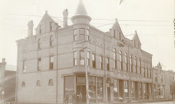 The buildings pictured made up what was called the Opera House Block, located at the intersection of Main and South Second Streets. The businesses housed there at the time included: Gustave M.  Helland, pharmacist; Dr. Carl Scholts, dentist; Gilbert and Jackson, attorneys; J. Theodore Dahl, Clothier; and Holstein Brager, jeweler. The buildings on the extreme right are the Mt. Horeb Bank and John Pieh's Meat Market. Partially visible at the extreme left is Guier's Hardware store.