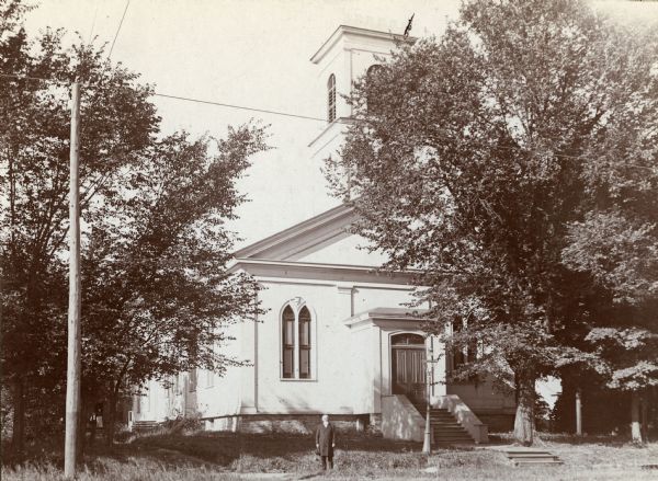 Front view of East Wisconsin Avenue Methodist Church. A man is standing on the sidewalk in front.