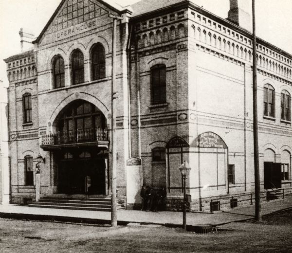 View from intersection towards the Oshkosh Grand Opera House on a street corner. The building was started in 1882 and finished in the following year at a cost of $36,000. It measures 60 x 120 feet. This photograph was taken shortly after it officially opened on August 9, 1883.