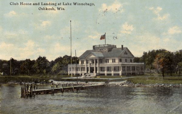 View across water towards a pier and the Yacht Club at the shoreline of Lake Winnebago. There is a widow's walk on the roof. Caption reads: "Club House and Landing at Lake Winnebago, Oshkosh, Wis."