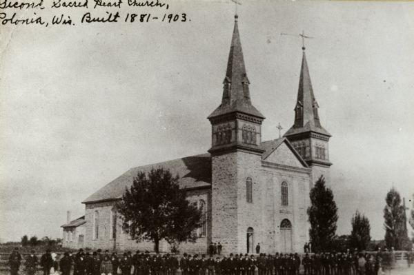 Exterior view of the Second Sacred Heart Polish Catholic Church. A large group of people are standing in the foreground. Caption reads: "Second Sacred Heart Church, Polonia, Wis. Built 1881-1903."
