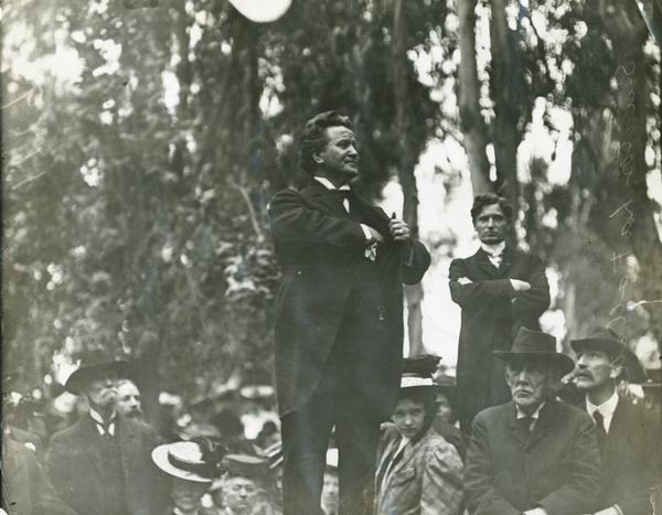 Senator Robert M. La Follette, Sr., addressing a crowd in a Los Angeles park.  This view, which is similar to ID# 30219, shows La Follette reaching into his pocket, perhaps for a handkerchief, and shows some of his audience.