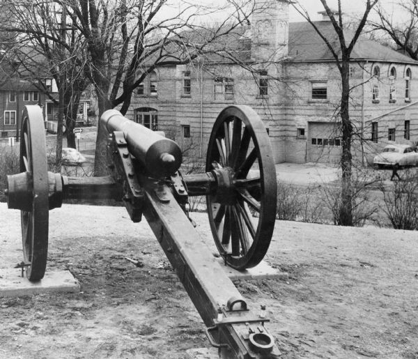A Civil War cannon captured at the Battle of Shiloh, displayed at Camp Randall near the corner of Randall Street and Dayton Street. A fire station is visible in the background.