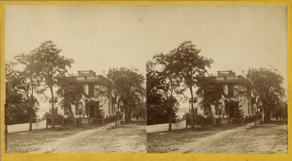 Stereograph of the Fairchild Residence, 302 Monona Avenue, at the intersection of Wilson Street. It was built around 1850 by Jarius C. Fairchild, Madison's first mayor. It later served as the home of his son, General Lucius Fairchild, who was governor of Wisconsin from 1866-1872.