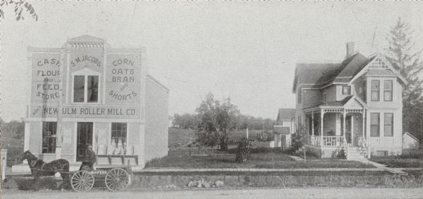 The Smith M. Jacobs Flour and Feed Store (left) and residence (right), 301 and 303 Monroe Street. The address renumbered within the next five years to 1701 and 1705 Monroe Street, respectively. The image shows a view looking southeast near the intersection of Garfield Street.  Jacob's home and business were located in what was then the suburb of Wingra Park. He used this halftone photograph in his advertising.
