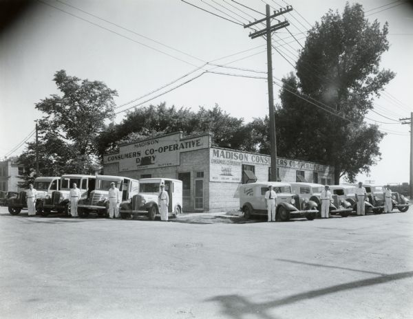 Exterior of the Madison Consumers Dairy Co-operative, probably located at 102 South Dickinson Street, with the milkmen posing next to their home delivery trucks--all Internationals.