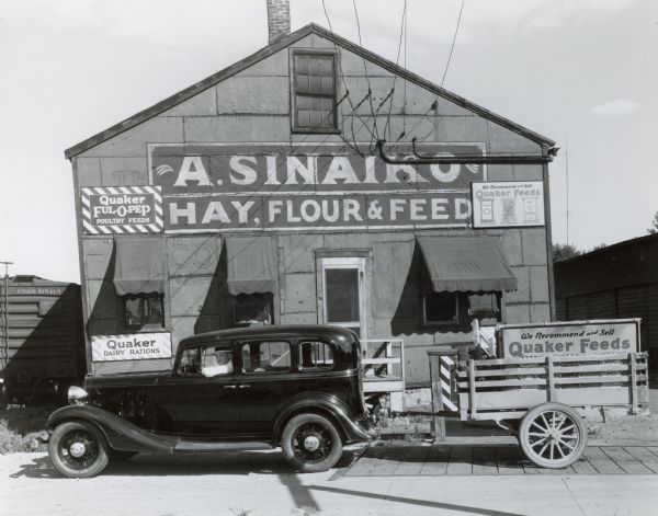 A man in a car poses in front of A. Sinaiko Hay, Flour and Feed at 653 West Washington Avenue.