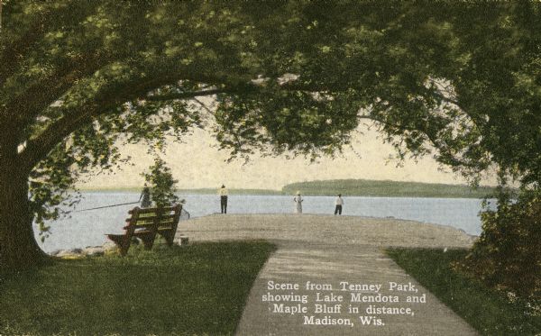 A scenic view down sidewalk towards Lake Mendota. People are standing and looking out towards Maple Bluff in the distance. Caption reads: "Scene from Tenney Park, showing Lake Mendota and Maple Bluff in distance, Madison, Wis."
