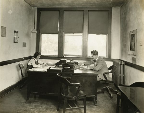 Interior of the company president's office. President Martin P. Winther and a female worker are seated at desks.