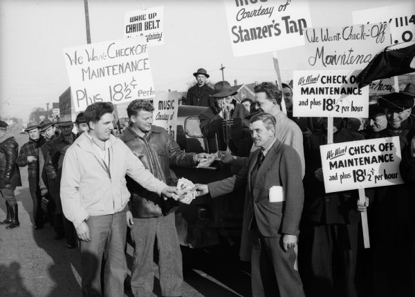 Del Krause, president of Local 1114, United Steelworkers of America (second from left) smiles as he and Ken Gorman, vice-president of the local, hand $800 to Howard Johnson, vice-president, and Sid Ray, president, of striking Chain Belt [Co.] Local 1527.  The gift followed a parade of 1000 Harnischfeger workers to the struck plant.  Wisconsin CIO News.