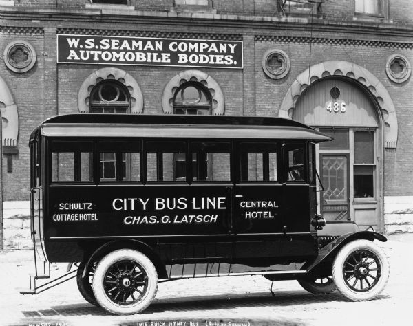 A 1915 Buick Jitney Bus for the Milwaukee City Bus Line.  Its body was produced by the W.S Seaman Company. The building in the background has a sign that reads: "W.W. Seamon Company Automobile Bodies."